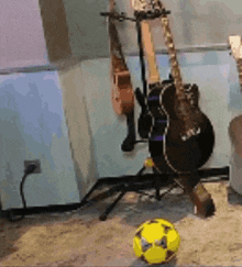 a soccer ball is sitting on the floor in front of a guitar rack .