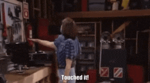a man and a woman are standing in a garage and the woman says touched it