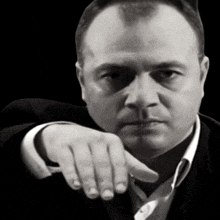a man in a suit is pointing his finger at the camera