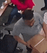 a man is holding a cardboard box in an office while a woman sits at a desk .