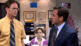 a man in a suit stands next to a woman in a pink shirt