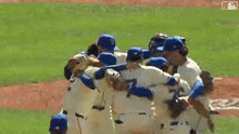 a group of baseball players are hugging on the field .