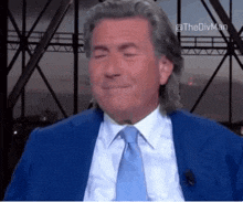 a man in a blue suit and tie is smiling with his eyes closed ..