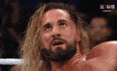 a wrestler with long blonde hair and a beard looks up