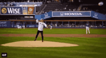 a man is throwing a ball on a baseball field with ads for honda and wise in the background