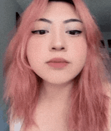 a close up of a woman 's face with pink hair and black eyes .