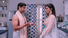a man and a woman are standing in a kitchen talking to each other