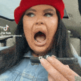 a woman wearing a red hat is holding a cell phone in her hand