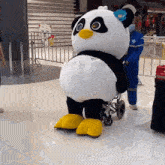 a panda mascot in a wheelchair is being pushed by a man