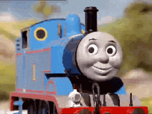 thomas the train is smiling and looking at the camera while sitting on the tracks .