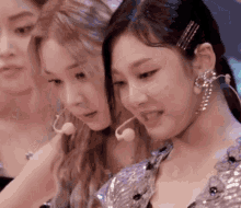 a group of women are standing next to each other and one of them is wearing a microphone in her ear .