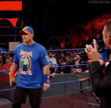 a man wearing a blue shirt that says respect pain it is walking in a wrestling ring .