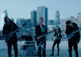 a group of people playing guitars and drums with a city skyline in the background