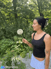 a woman blowing a dandelion with a momento logo in the corner