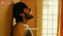 a man with a beard is screaming while leaning against a wall .