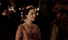 a woman in a red dress and a tiara is standing next to a man in a brown jacket .