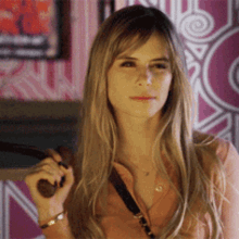 a woman with long blonde hair is holding a brown object