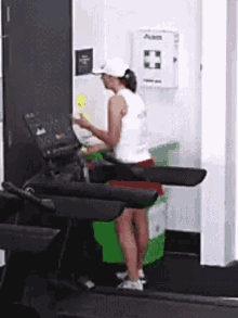 a woman is standing on a treadmill in a gym while cleaning it .