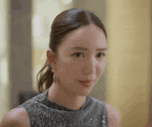 a woman wearing a ponytail and earrings looks at the camera