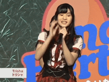 a girl singing into a microphone with the name trisha on the bottom right