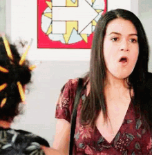 a woman is making a funny face in front of a painting of an arrow