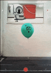 a green balloon with a face drawn on it is floating in the air