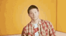 a man in a plaid shirt is giving a thumbs up .