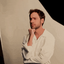 a man with a beard wearing a white shirt is pointing at something