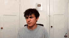 a young man with curly hair and a nose ring is sitting in a chair .