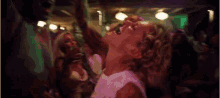 a crowd of people are dancing in a dark room with their arms in the air .