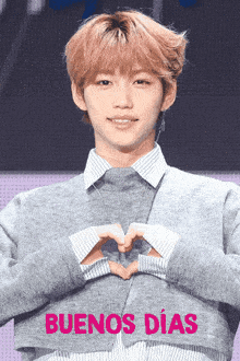 a man making a heart shape with his hands and the words buenos dias