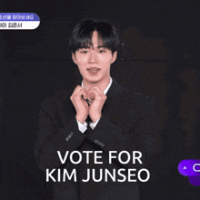a man in a suit and tie making a heart with his hands and says vote for kim junseo
