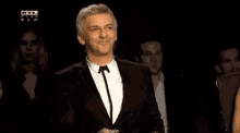 a man in a suit and tie is smiling while standing in front of a crowd .