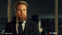 a man with a beard wearing a suit and tie with #suitsla