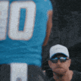 a man wearing sunglasses and a hat is standing next to a football player wearing a number 10 jersey .
