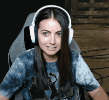 a woman wearing headphones and a tie dye shirt is sitting in a chair