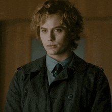 a man with curly hair wearing a black jacket and tie