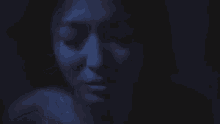 a close up of a woman 's face with her eyes closed in the dark
