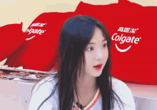 a woman sitting in front of a colgate advertisement