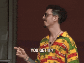 a man in a hawaiian shirt says " you get it "