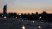a blurry picture of a city skyline at sunset with a string of lights in the foreground