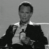 a man in a suit holds a bottle of atomic