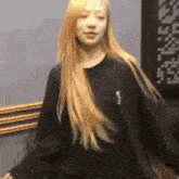a woman with long blonde hair is wearing a black sweatshirt and dancing .