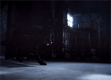 a person standing in a dark room with a light shining through a window