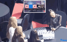 a group of women sit around a table with bottles of water