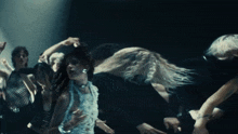 a group of people are dancing in a dark room with a woman in the foreground
