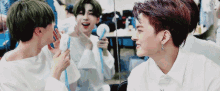 two young men are standing next to each other in front of a mirror and one of them is holding a fan .