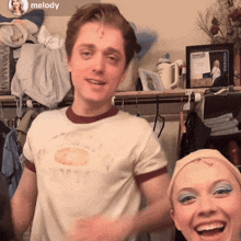 a man wearing a white shirt that says melody stands next to a woman