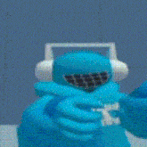 a blue stuffed animal with headphones and a helmet is laying on a bed .