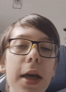 a close up of a person wearing glasses with a yellow sticker on their nose .